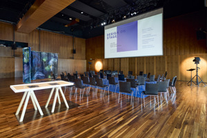Vortragsbestuhlung auf einem blauen Teppich mit großer Leinwand im Seestudio im Festspielhaus Bregenz