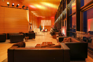 Seefoyer im Festspielhaus Bregenz in Weihnachtsstimmung mit schwarzen Loungemöbeln und Lagerfeuer auf dem Großbildschirm