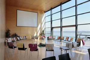Ein großer Stuhlkreis mit bunten Decken über den Stuhllehnen und Leinwand im Seefoyer im Festspielhaus Bregenz