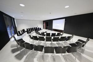 Dreireihige Stuhlreihen im Halbkreis vor einer Leinwand aufgestellt in der weißen Seegalerie im Festspielhaus Bregenz