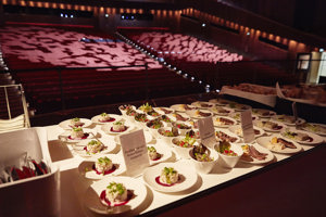 Ein Tisch mit verschiedenen Speisen auf weißen Tellern auf der Hauptbühne mit Blick in den Großen Saal