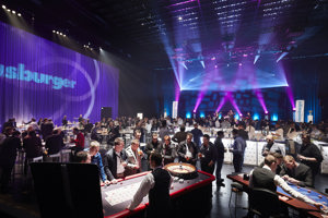 Menschen an Casino-Spieltischen in der violett eingeleuchteten Werkstattbühne im Festspielhaus Bregenz