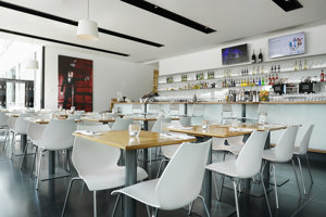 Holz-Tische mit weißen Stühlen und eine lange Bar im Restaurant buehnedrei im Festspielhaus Bregenz