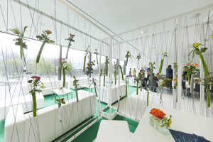 Weiße Lounge-Sitzmöbel mit hellgrünem Teppich und Rosen im Saal Panorama mit Blick auf den Platz der Wiener Symphoniker