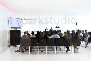 Tagungsteilnehmer:innen in Reihenbestuhlung vor einem Rednerpult im weißen Parkstudio des Festspielhauses Bregenz