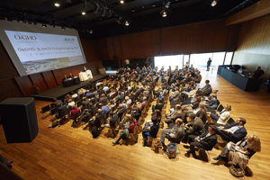 Vollbesetzte Reihenbestuhlung, eine Bühne mit Stehtischen und einem Podium und Leinwand im Seestudio im Festspielhaus Bregenz