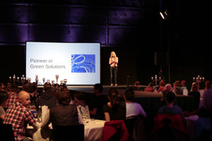 Eine Frau präsentiert auf einer Bühne vor einer großen Leinwand auf der Werkstattbühne im Festspielhaus Bregenz