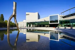Außenansicht des Festspielhaus Bregenz bei Tag, im Vordergrund die Skulptur Ready Maid und Stühle rund um den Brunnen © Anja Koehler