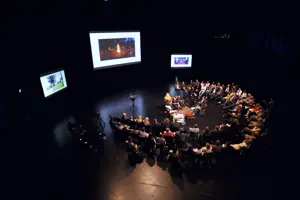 Fishbowl-Teilnehmer:innen sitzen in einem zweireihigen Stuhlkreis um ein Podium auf der Hauptbühne im Festspielhaus Bregenz © Lucas Breuer