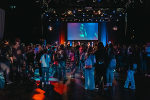 Junge Besucher:innen tanzen vor einer Bühne mit großer Leinwand auf der Werkstattbühne im Festspielhaus Bregenz