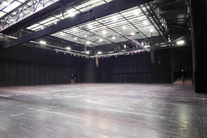 Leere Werkstattbühne mit schwarzem Boden, Bühnenvorhängen und Gitterboden-Deckenkonstruktion.