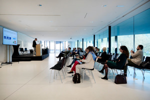 Reihenbestuhlung vor einer Bühne mit Rednerpult und Leinwand