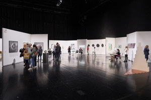 Ausstellungsbesucher:innen stehen vor Exponaten auf der Werkstattbühne im Festspielhaus Bregenz