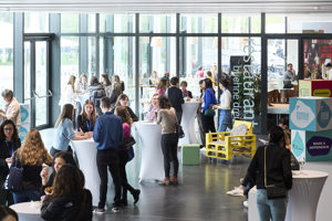 Menschen an Stehtischen mit weißen Hussen im Eingangsfoyer des Festspielhauses Bregenz