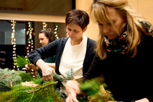 Drei Frauen arbeiten konzentriert an ihren Adventkränzen im Festspielhaus Bregenz