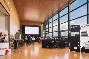 Tagungsteilnehmer:innen in Reihenstuhlung im Seefoyer im Festspielhaus Bregenz mit Blick auf den See © Angela Lamprecht