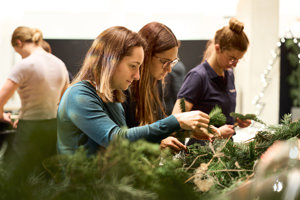 Teilnehmerinnen arbeiten konzentriert an Adventkränzen beim Adventhock im Festspielhaus Bregenz
