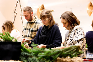 Advent-Hock Teilnehmer:innen arbeiten konzentriert an ihren Advent-Kränzen im Festspielhaus