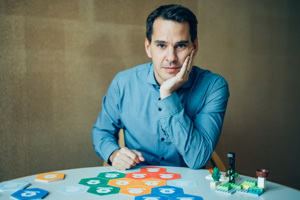 Ein Mann in blauem Hemd sitz an einem runden Tisch