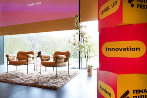 Zwei orange Sessel auf einem Hochflor-Teppich vor einer Glasfront mit Blick auf den Platz der Wiener Symphoniker