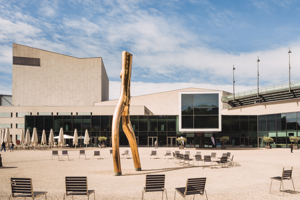 Festspielhaus Bregenz Vorplatz mit Stühlen und großer Skulptur und blauem Himmel mit Schleierwolken
