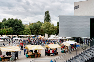 viele Besucher:innen zwischen Marktständen auf dem Vorplatz des Festspielhauses