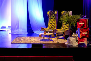 Zwei grüne Ohrensessel und ein niedriger Tisch auf der Vorbühne beim Health & Mind Festival 2023 im Festspielhaus Bregenz