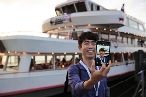 Ein Mann macht ein Selfie vor einem Schiff