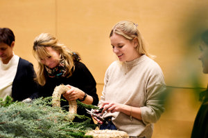 Zwei Frauen amüsiert beim Adventkranzbinden im Seefoyer des Festspielhauses Bregenz