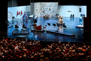 Notenpulte vor einer Kunstausstellung auf der Hauptbühne im vollbesetzten Auditorium im Großen Saal