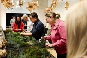Mehrere Personen binden konzentriert einen Adventkranz